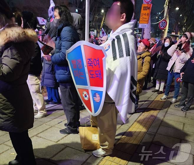 25일 서울시 종로구 안국역 일대에서 윤석열 대통령 탄핵에 반대하는 한 지지자가 '빨갱이는 죽여도 돼'라 적힌 방패 모양의 피켓을 들고 서 있다. 2025.02.25/ⓒ 뉴스1 권진영 기자