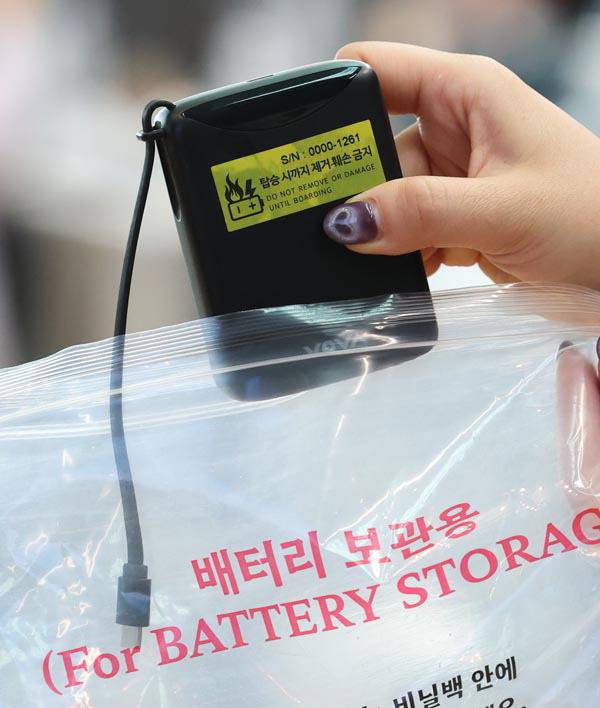 지난 1일 인천국제공항 대한항공 체크인 카운터에서 관계자가 보조배터리에 스티커를 부착한 뒤 비닐봉지에 넣는 모습.  연합뉴스