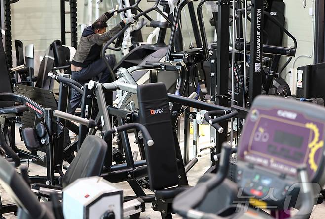 Used gym machines crowd a fitness equipment resale store in Yongin, Gyeonggi Province, on Feb. 3, as a worker arranges the inventory. (Newsis)