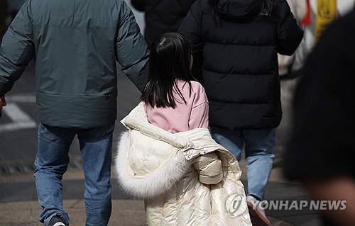 포근한 날씨를 보인 지난 2월 28일 서울 중구 명동 거리에서 한 아이가 외투를 반쯤 입은 채로 이동하고 있다. [연합뉴스]