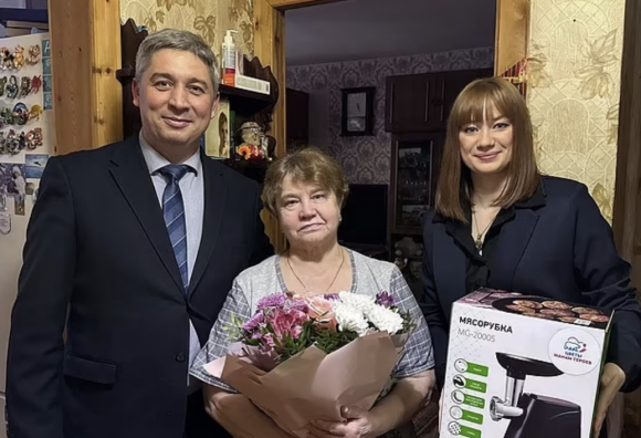 국제 여성의 날 캠페인의 목적으로 전쟁에서 아들을 잃은 한 어머니(사진 중앙)가 당국으로부터 받은 고기 분쇄기와 꽃을 선물 받고 촬영한 기념사진. SNS 캡처