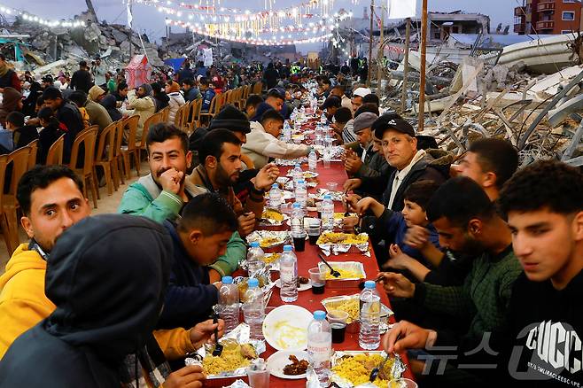 라마단 성월 동안 이스라엘과 하마스 간의 휴전 협정을 한 가운데 팔레스타인 사람들이 가자 지구 남부의 라파에서 건물 잔해 근처에서 이프타르 음식을 먹고있다. ⓒ 로이터=뉴스1