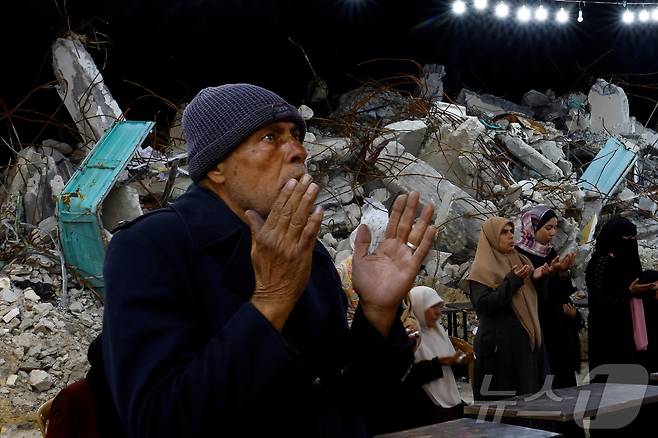 팔레스타인 시민들이 남부 가자 지구의 라파에서 이스라엘과 하마스 간의 휴전 기간 동안 건물 잔해 앞에서 기도를 하고 있다.ⓒ 로이터=뉴스1