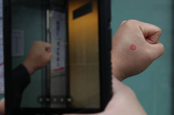 A voter takes a photo of a stamp showing off that they voted for the general election after exiting a polling station in Seocho District, southern Seoul on Wednesday. [NEWS1]