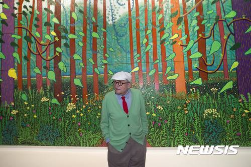 【파리=AP/뉴시스】영국 화가 데이비드 호크니가 26일(현지시간) 프랑스 파리의 퐁피두센터에 기증한 '이스트 요크셔 월드게이트에 도착한 봄(The Arrival of Spring in Woldgate, East Yorkshire)'앞에서 포즈를 취하고 있다. 2011년작인 이 그림은 32개의 패널로 이뤄져 있으며, 높이는 약 3m 길이는 약 10m에 이르는 대작이다.