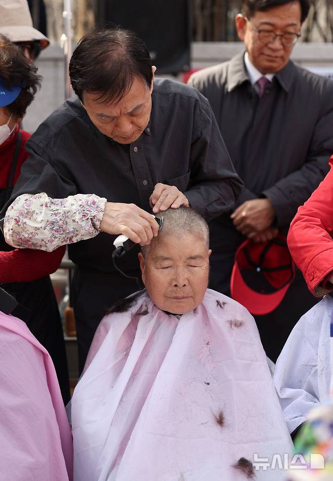 [서울=뉴시스] 김선웅 기자 = 헌재의 윤석열 대통령에 대한 탄핵심판 선고가 임박한 13일 서울 종로구 헌법재판소 앞에서 친 윤 성향 시민들이 탄핵을 반대하며 삭발을 하고 있다. 2025.03.13. mangusta@newsis.com