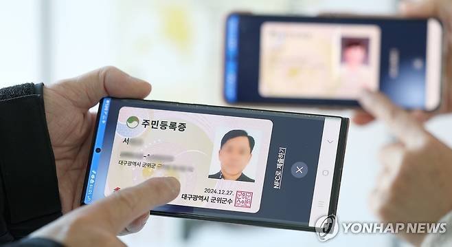 스마트폰으로 들어간 주민등록증 (대구=연합뉴스) 윤관식 기자 = 모바일 주민등록증 시범 발급이 시작된 27일 오전 대구 군위군 군위읍행정복지센터에서 시민들이 발급받은 모바일 주민등록증을 들어 보이고 있다.
    행정안전부는 세종시, 강원 홍천군, 경기 고양시, 경남 거창군, 대전 서구, 대구 군위군, 울산 울주군, 전남 여수시, 전남 영암군 등 9개 지자체를 대상으로 모바일 주민등록증을 시범 발급한다. 2024.12.27 psik@yna.co.kr