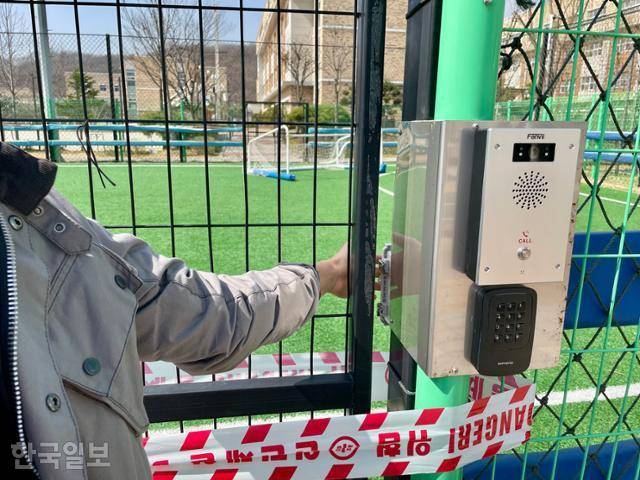 세종시 고운동 솔뜰근린공원 내 풋살장 출입문 모습. 그 오른쪽으로 인터폰이 있고, 그 뒤(내부)에 문을 열 수 있는 스위치가 있다. 어른도 손을 안쪽으로 넣어 내부의 개폐 스위치를 조작할 수 있다. 사진에 보이는 벨을 누르면 관리실 직원이 인터폰을 받는다. 그 직원은 인터폰에 장착된 폐쇄회로(CC)TV와 별도 설치된 카메라를 통해 풋살장을 볼 수 있다고 했다. 사전 예약되지 않은 시간에 풋살장 문이 열리면 관리실에서 그 사실을 확인할 수 있느냐는 질문에는 답하지 않았다. 세종=정민승 기자