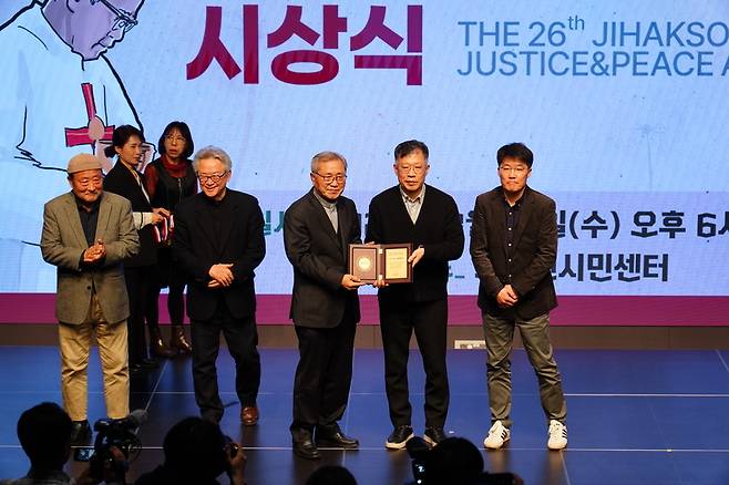 14일 서울시 종로구 노무현시민센터에서 열린 제26회 지학순정의평화상 시상식에서 박중석 뉴스타파 대표(오른쪽 두 번째)가 상을 받고 있다. 시상자는 저스피스 이사인 최기석 신부. /저스피스 제공