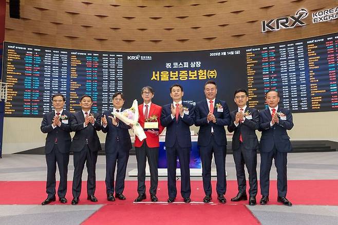 [서울=뉴시스] 14일 오전 서울 여의도 한국거래소에서 열린 서울보증보험 유가증권시장 신규상장식에서 이명순 서울보증보험 대표이사(왼쪽에서 4번째)와 관계자들이 기념 촬영을 하고 있다. (사진=서울보증보험 제공) 2025.03.14. photo@newsis.com *재판매 및 DB 금지
