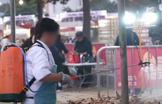 지난 2023년 11월 홍성 글로벌 바비큐 축제에서 더본코리아 직원으로 추정되는 사람이 농약 분무기에 사과주스를 담아 바비큐에 살포하는 모습. 사진 백종원 유튜브 채널 캡처