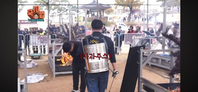 더본코리아 직원으로 추정되는 사람이 농약 분무기로 사과주스를 살포하고 있다. 유튜브 채널 '백종원' 캡쳐.