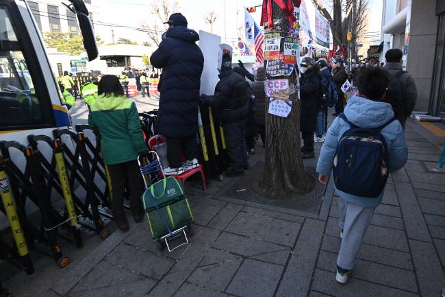 등굣길 탄핵시위 헌법재판소의 윤석열 대통령 탄핵심판 선고가 임박한 17일 오전 서울 종로구 헌재 앞에서 탄핵반대를 주장하는 윤 대통령 지지자들이 집회를 열고 있는 가운데 인근 초등학교 학생이 등교를 서두르고 있다.  백동현 기자