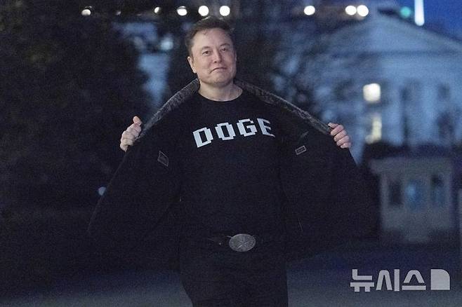 [워싱턴=AP/뉴시스]일론 머스크가 지난 9일(현지시각) 백악관에서 정부효율화부(DOGE)라는 글자가 크게 새겨진 티셔츠를 기자들에게 자랑하고 있다. 머스크의 사회복지 삭감 발언을 둘러싸고 민주당과 백악관이 치열한 공방전을 벌이고 있다. 2025.3.12.