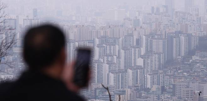 12일 서울 중구 남산에서 한 시민이 아파트단지 일대를 촬영하고 있다. 뉴스1