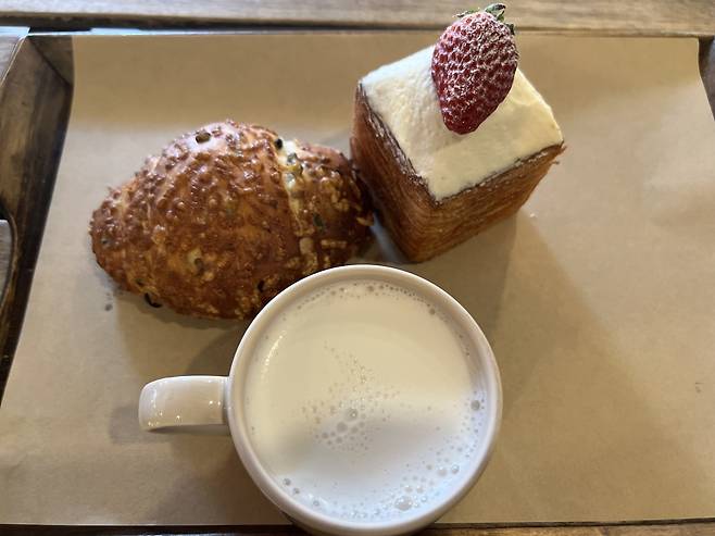 (Clockwise from top right) A fresh strawberry cream pastry, cup of milk and cheese olive salt bread are served at Soha Salt Pond in Ikseon-dong, Jongno-gu, central Seoul. (Park Jun-hee/The Korea Herald)