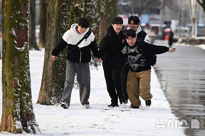 [광주=뉴시스] 박기웅 기자 = 눈이 내린 18일 오전 광주 북구 용봉동 전남대학교 정문에서 대학생들이 눈길을 밟으며 등교하고 있다. 2025.03.18. pboxer@newsis.com