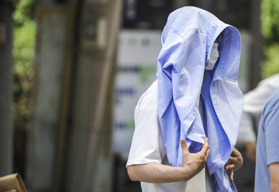 서울을 비롯한 대부분의 지역에 폭염주의보가 발령된 19일 서울 영등포구 여의도환승센터에서 한 시민이 옷으로 햇빛을 가린 채 이동하고 있다.(사진=연합뉴스)
