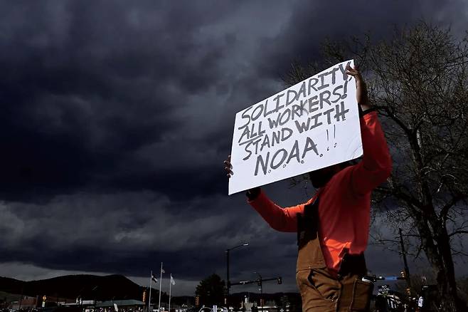 한 남성이 지난 3일 콜로라도주 볼더에 위치한 국립해양대기청(NOAA) 밖에서 열린 대규모 집회에서 NOAA의 인력 감축에 항의하는 손팻말을 들고 있다. 앞서 도널드 트럼프 행정부는 세계 최고의 기후과학 연구·측정 기관인 국립해양대기청에서 800여명의 직원을 해고했다.  [게티 이미지]