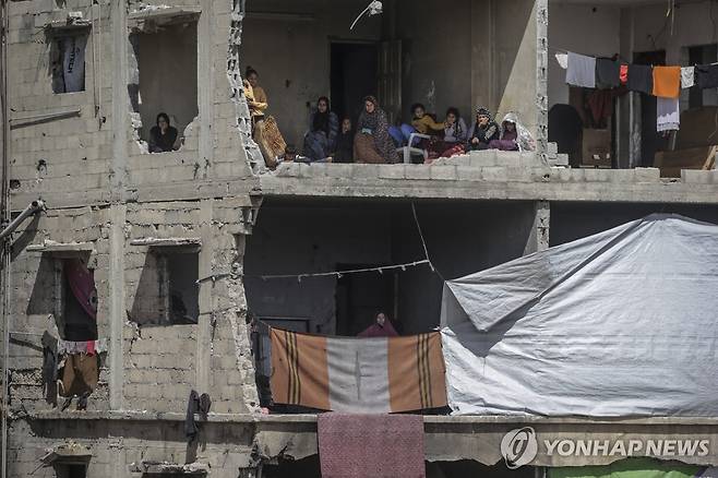 19일(현지시간) 이스라엘의 공습으로 파괴된 팔레스타인 가자시티 주택. 가족들이 무너진 집 안에 앉아 사망자 수색 작업을 지켜보고 있다.  [EPA 연합뉴스]