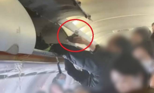 승객 등이 짐칸의 화재를 진화하는 모습. 승객 등이 건네는 손에 음료로 추정되는 병이 보인다. ('X'캡처)