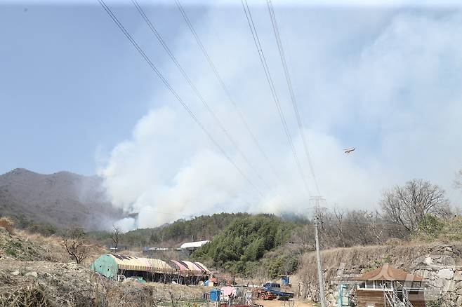 울산 울주 온산읍 운화리 산불이 이틀째에 접어든 23일 인근 마을에 연기가 자욱한 상태다. 마을 위로는 헬기가 화재 현장으로 출동하고 있다. 2025.3.23/뉴스1 ⓒ News1 김세은 기자