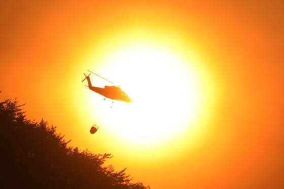경남 산청 대형 산불이 사흘째로 접어든 23일 오후 산청군 단성면 일대에서 산불진화 헬기가 진화작업을 벌이고 있다. [뉴스1]