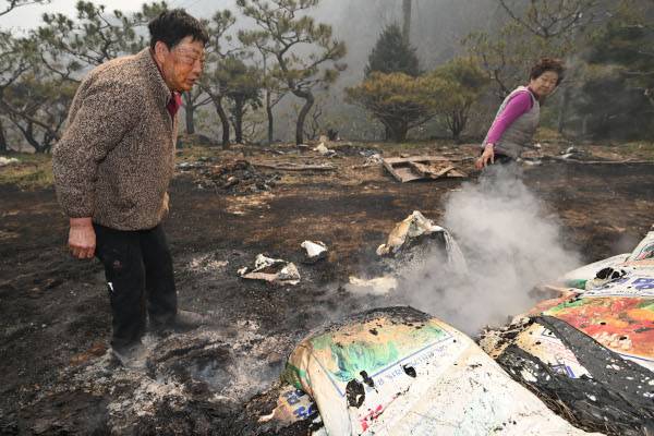 경남 산청군 중태마을 주민 손성주(왼쪽)씨가 23일 자신의 집 마당에서 연기가 피어오르는 비료 포대를 망연자실한 표정으로 바라보고 있다. 손씨는 간밤에 주택 인근으로 번진 불을 끄다가 얼굴에 화상을 입었다. 산청=윤웅 기자