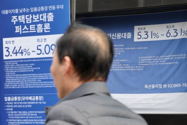 한 시민이 2일 서울 시내 은행에 붙은 대출 상품 현수막 앞을 지나고 있다. 연합뉴스