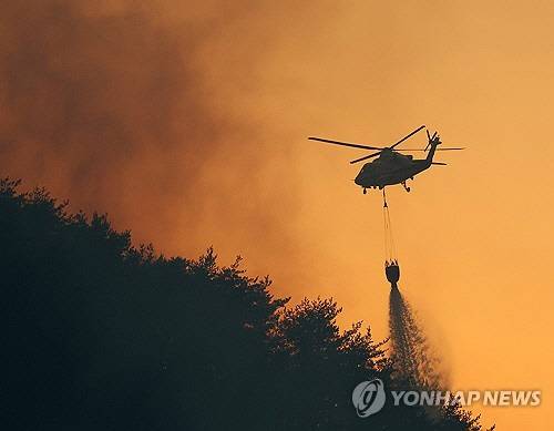 경남 산청군에서 발생한 산불 사흘째인 지난 23일 경남 산청군 단성면 야산으로 번진 산불을 헬기가 물을 뿌려가며 진화하고 있다. [산청=연합뉴스]