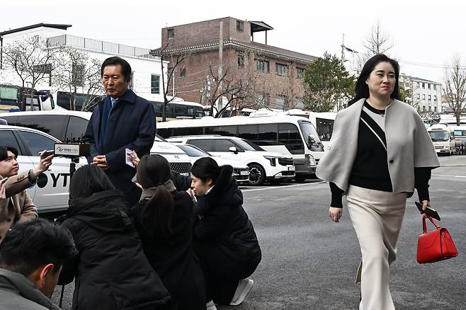 18일 서울 종로구 헌법재판소에서 열린 박성재 법무부 장관 탄핵 심판 첫 변론에 국회 탄핵소추위원장인 정청래 더불어민주당 의원이 참석하며 입장을 밝히고 있는 가운데 변론을 방청하러 온 김계리 변호사가 웃으며 지나가고 있다. 2025.3.18. / 고운호 기자