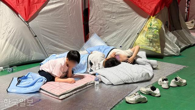 26일 경북 영양군 영양군민회관에 산불을 피해 모인 아이들이 임시로 마련된 텐트 앞에 누워 있다. 영양=문지수 기자