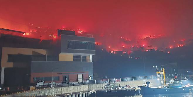 26일 새벽 경북 영덕군 영덕읍 석리. 마을 뒷산까지 타들어온 시뻘건 불길이 바닷가 마을을 금방이라도 덮칠 듯 하다. 영덕읍내로 대피한 한 주민은 “육로 대피가 어려워 (바다로 나가) 배를 타고 대피해야만 했다”고 긴박했던 상황을 설명했다.  [독자 제공]