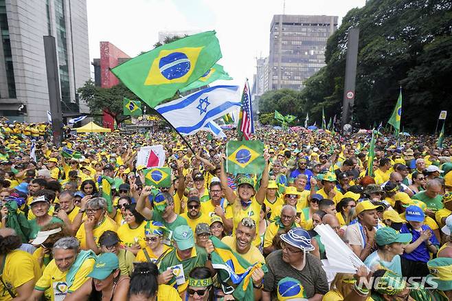 [상파울루=AP/뉴시스] 자이르 보우소나루 전 브라질 대통령 지지자들이 2024년 2월 25일 상파울루에서 열린 집회에 참석해 환호하고 있다. 쿠데타 모의 의혹과 귀금속 불법 반입 등의 혐의로 검찰 조사를 받고 있는 보우소나루 전 대통령은  3월 25일부터 대법원의 심판을 받게 된다. 2025.03.26.