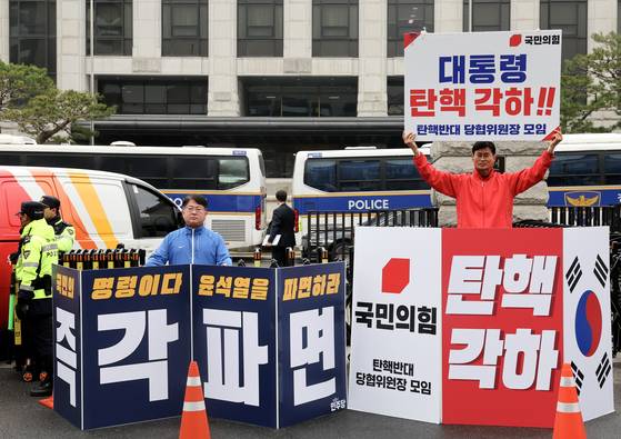 국민의힘 관계자과 더불어민주당 관계자가 27일 오전 서울 종로구 헌법재판소 앞에서 윤석열 대통령 탄핵을 두고 각하와 파면을 촉구하며 피켓 시위를 하고 있다. 전민규 기자