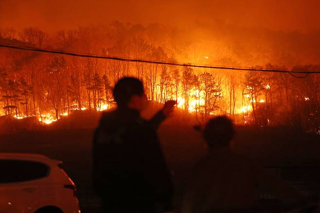 25일 경북 안동시 남선면 마을에서 주민들이 야산에 번진 산불을 바라보고 있다. [연합]