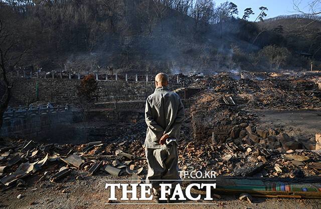 의성 산불이 발생한지 5일째를 맞은 26일 오후 경북 의성군 단촌면 고운사에 번진 산불로 가운루와 종각 등 건물들이 불에 타 흔적만 남은 가운데 고운사 스님이 화재 현장을 바라보고 있다. /박헌우 기자