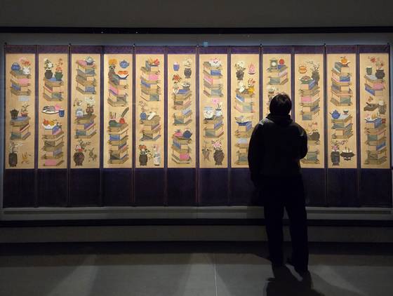 아모레퍼시픽미술관 '조선민화전'에서 관람객이 국립중앙박물관 소장 '책거리 12폭 병풍'을 바라보고 있다. 1918년 작으로 근대 서양 문물이 기물에 포함된 것이 흥미롭다. 문소영 기자