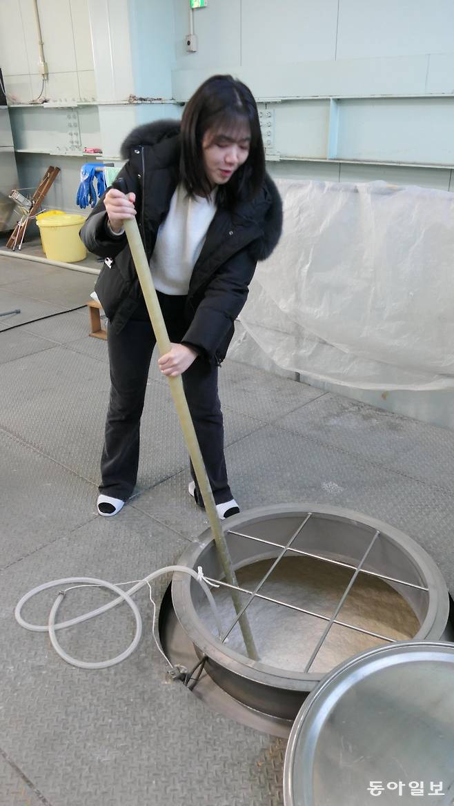 한 관광객이 니가타현 니가타시 다카노주조의 발효 탱크에 담긴 모로미(술밑)를 저어 거품을 제거하는 카이이레 작업을 해 보고 있다.