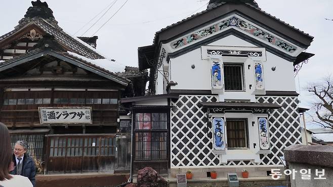 니가타현 세타야 발효·양조 마을의 옛 사프란슈 양조장 건물(왼쪽)과 곳간(오른쪽). 곳간 창문 여닫이 덮개의 고테에 작품이 눈에 띈다.