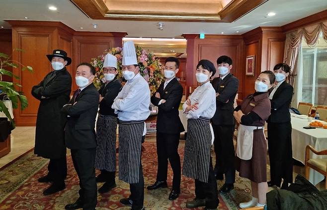 2021년 12월 정리해고 통보를 받은 세종호텔지부 조합원들이 퇴사 직전 다양한 호텔 유니폼을 입고 촬영한 단체 사진. 일식 요리사인 고진수 지부장(맨 왼쪽)은 이날 도어맨 복장을 입고 사진 촬영을 했다. 출처 : 스튜디오R