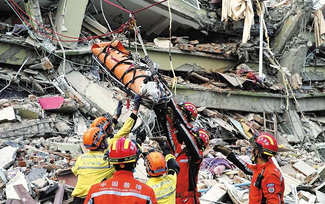 31일 미얀마 제2의 도시 만달레이의 지진 피해 현장에 출동한 중국 구조대원들이 무너진 건물 더미에서 발견된 생존자를 들것에 실어 이송하고 있다. 이 지역 건물 대다수는 내진 설계가 되어 있지 않았다고 외신들은 전했다. 사흘 전 규모 7.7의 강진이 도시를 강타한 뒤 매몰자 생존 골든타임인 72시간을 넘기면서 희생자가 급격히 늘어날 것이라는 우려가 커지고 있다. /신화 연합뉴스