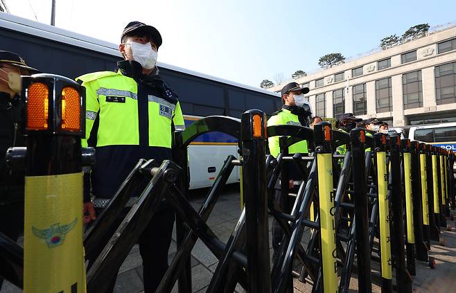 21일 서울 종로구 헌법재판소 정문에 세워진 경찰버스 앞에서 경찰들이 경계근무를 서고 있다. <연합뉴스>