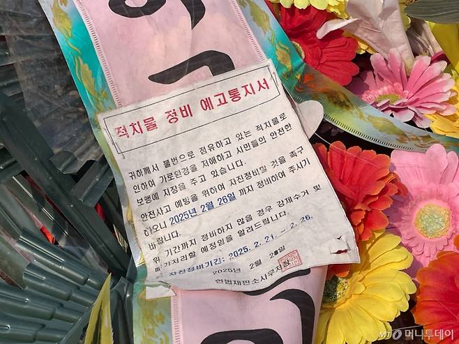 2일 오전 서울 종로구 헌법재판소 앞에 놓여진 화환에 헌법재판소 측이 붙인 적치물 정비 예고통지서. 지난 2월26일까지 자진정비 기간이었다. /사진= 이지현 기자.