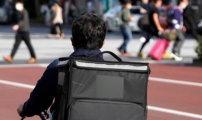 일본의 음식 배달 대행 업체 데마에칸이 고객에게 배달한 음식 봉투 안에 쥐가 들어가는 일이 발생해 사과했다. 사진은 도쿄 신주쿠 거리의 한 음식 배달원 모습. AP연합뉴스
