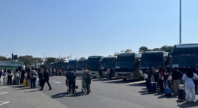공항 밖, 전세버스들이 길게 줄지어 서 있다. 학생들은 반별로 모여 탑승 순서를 기다리는 중이다. (제주도관광협회 제공)