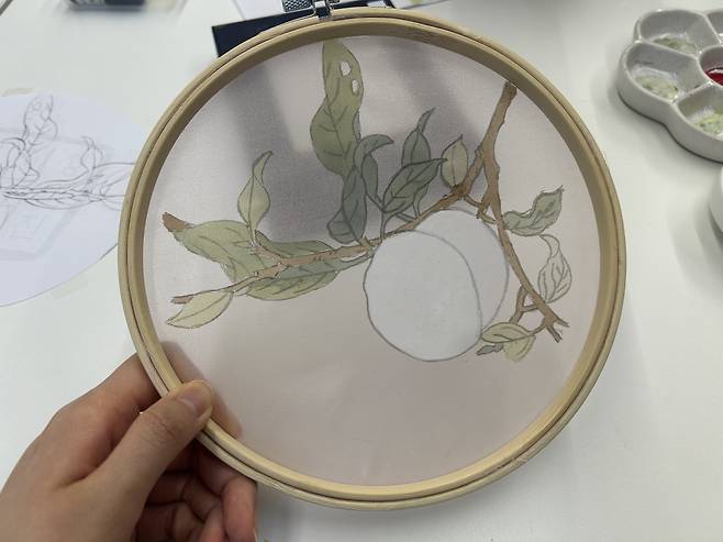 In the process of making my first jinchae (silk painting), I tried baechae, or the traditional technique of coloring on the back of the sheer silk. Here, I flipped over my painting to the back and colored the peach in white. [SHIN MIN-HEE]