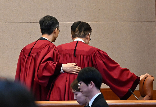 4일 헌법재판소 대심판정에서 윤석열 대통령에 대해 파면 결정을 선고한 뒤 김형두 헌법재판관의 어깨를 두드리며 문형배 헌법재판소장 권한대행(왼쪽)이 퇴장하고 있다. [사진 출처 = 사진공동취재단, 연합뉴스]