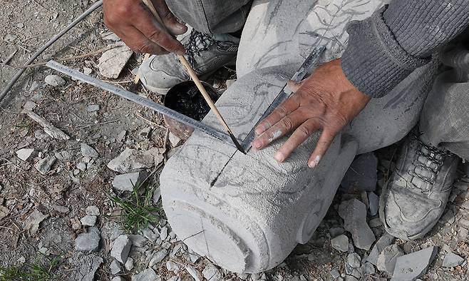 축소 재현 조성 중인 미륵불 부처에 고석산 석장이 자로 크기를 표시하고 있다.