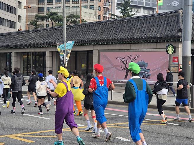 6일 오전 서울 종로구 광화문광장에서 열린 ‘2025 더 레이스 서울 21K’ 마라톤 대회에서 참가자들이 광장을 출발해 도심을 달리고 있다.  게임 캐릭터 ‘마리오, 루이지, 와리오’오‘복자을 한 참가자가 달리고 있다. 김도윤 기자.